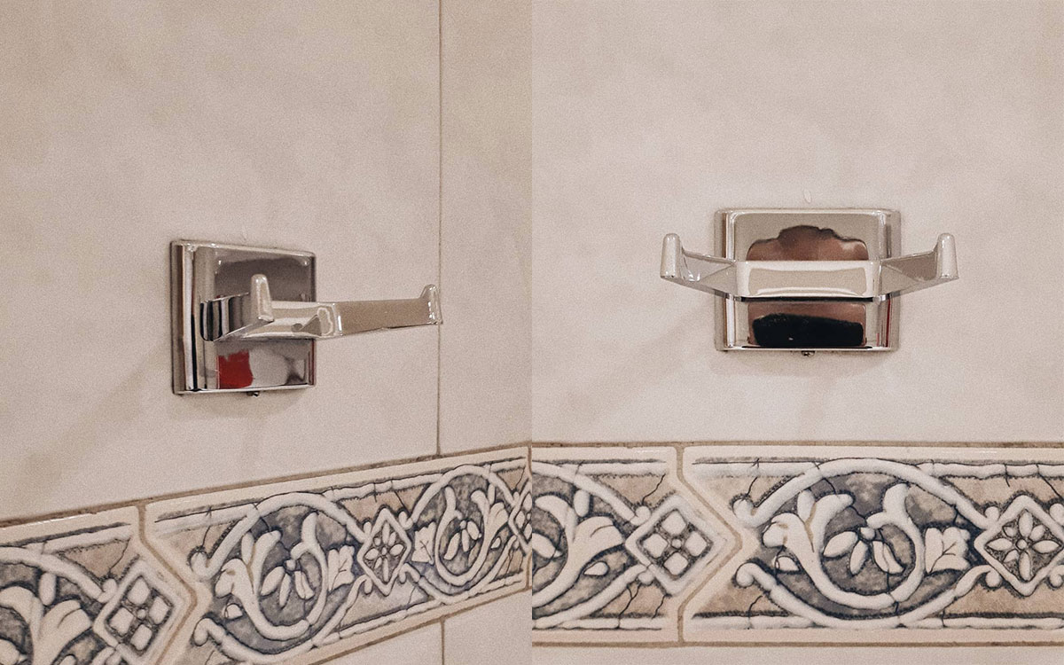 A double hook made of metal, chrome, screwed to the wall. Found on a public bathroom in Mexico City, Mexico, 2019.