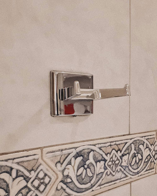 A double hook made of metal, chrome, fixed to a wall. Found on a restaurant in Mexico City, Mexico, 2019.