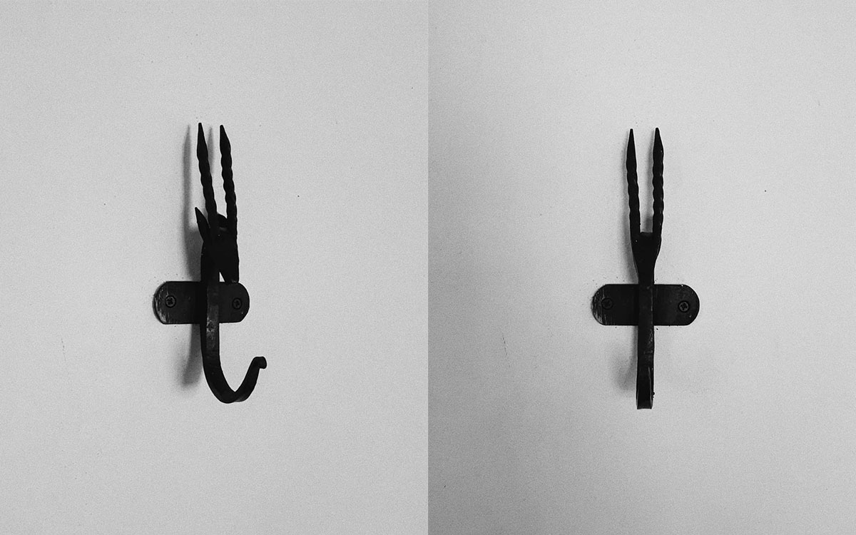 A single hook made of metal, black paint, screwed to a wall. Found on a private home in Malinalco, Mexico, 2020.
