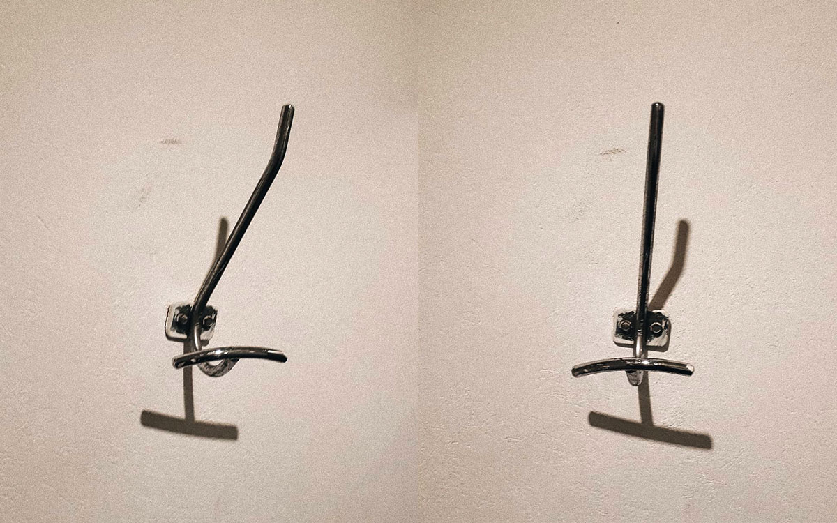 A double hook made of metal, chrome, screwed to a wall. Found on a private home in Mexico City, Mexico, 2020.