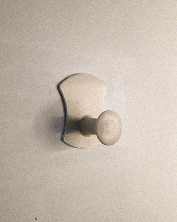 A single hook made of beige plastic, fixed to a door. Found on a private home in Lyon, France, 2020.