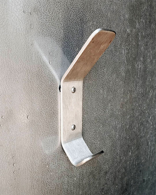 A double hook made of metal, riveted to a door. Found on a public bathroom in Lyon, France, 2020.