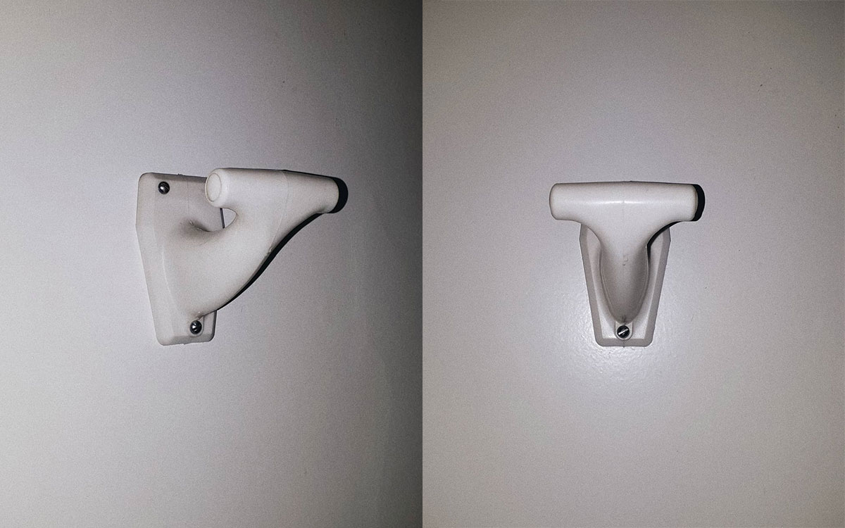 A single hook made of white plastic, screwed to a door. Found on a private home in Val-d'Isère, France, 2020.