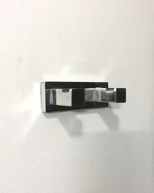 A double hook made of metal, chrome, fixed to a wall. Found on a private home in Mexico City, Mexico, 2021.