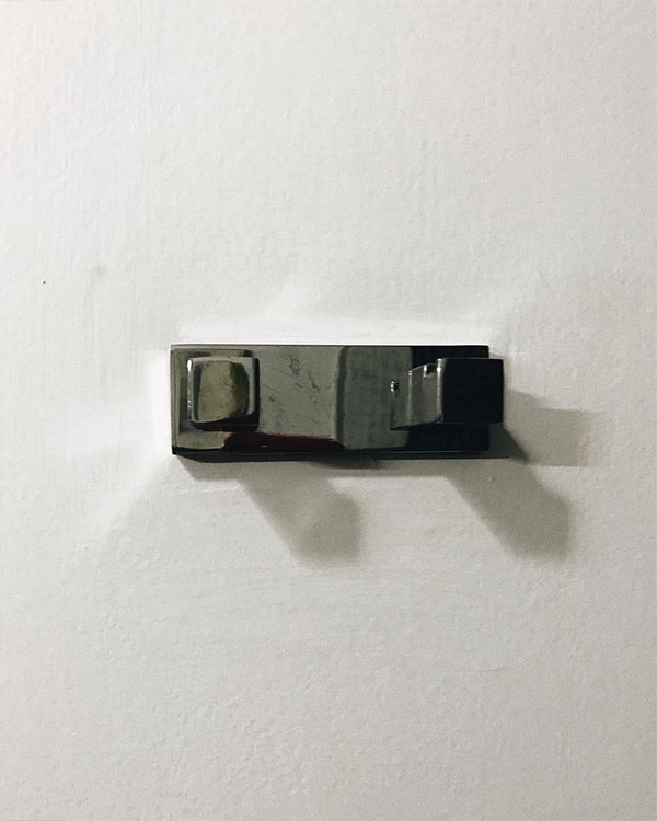 A double hook made of metal, chrome, fixed to a wall. Found on a private home in Mexico City, Mexico, 2021.