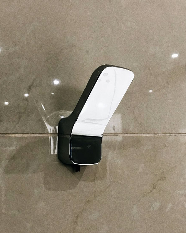 A single hook made of metal, chrome, screwed to a wall. Found at Club Mundet in Mexico City, Mexico, 2021.