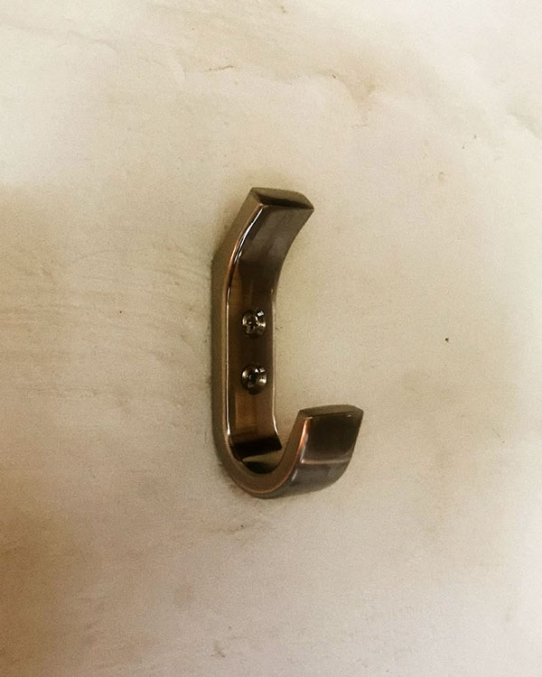 A double hook made of metal, brass, screwed to a wall. Found on a private home in Malinalco, Mexico, 2021.