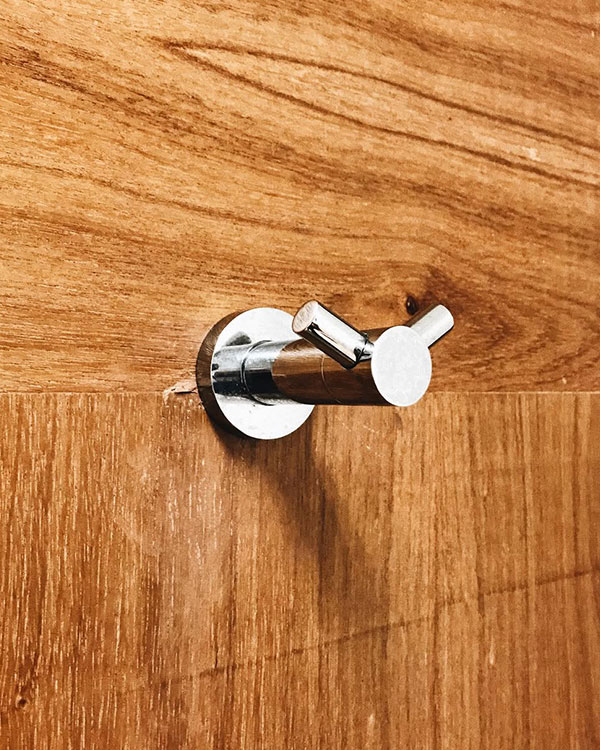 A double hook made of metal, chrome, screwed to a door. Found on a hospital in Mexico City, Mexico, 2022.