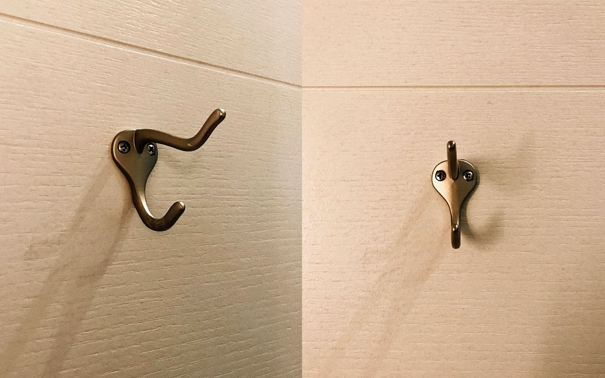 A double hook made of metal, brass, screwed to a door. Found on a private home in New York, USA, 2022.