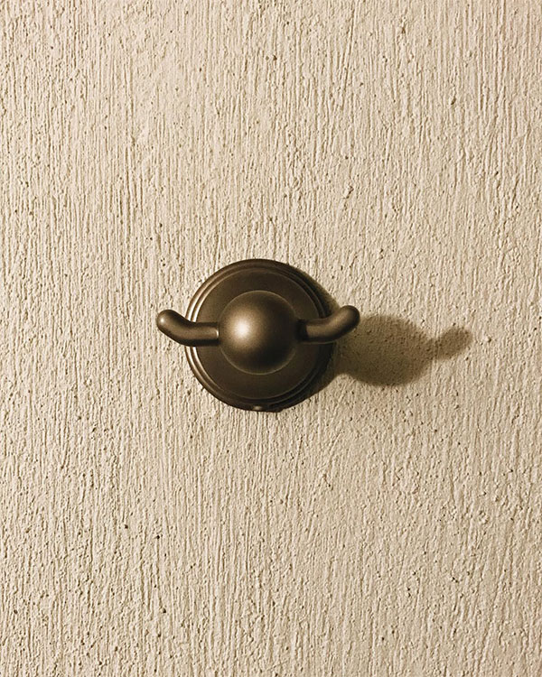 A double hook made of metal, brass, fixed to a wall. Found on a private home in Aguascalientes, Mexico, 2022.