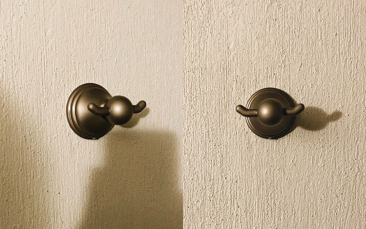 A double hook made of metal, brass, screwed to a wall. Found on a private home in Aguascalientes, Mexico, 2022.