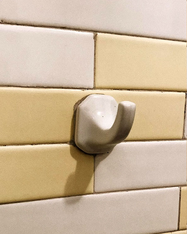 A single hook made of stoneware, white enamel, fixed to a wall. Found on a private home in Aguascalientes, Mexico, 2022.