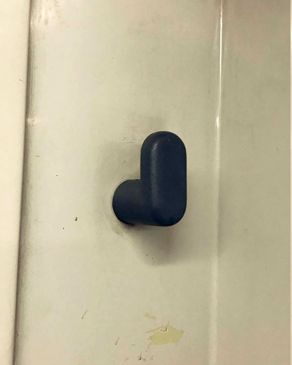 A single hook made of gray plastic, fixed to a wall. Found on a train near Barcelona, Spain, 2022.
