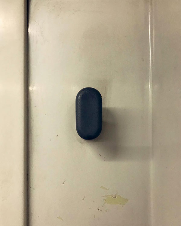 A single hook made of gray plastic, fixed to a wall. Found on a train near Barcelona, Spain, 2022.