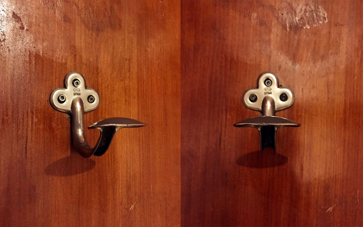 A single hook made of metal, brass, screwed to a door. Found on a restaurant in Barcelona, Spain, 2022.