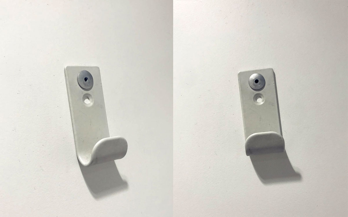 A single hook made of white plastic, riveted to a door. Found on a public bathroom in Avignon, France, 2022.