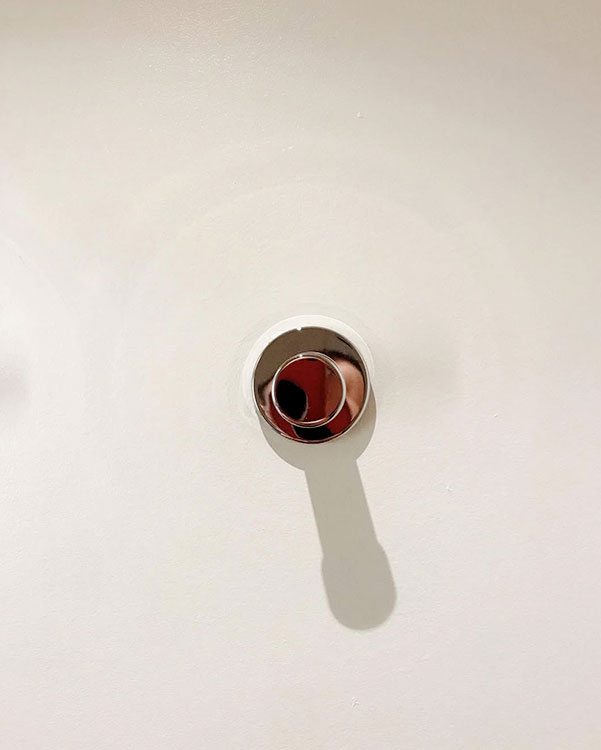 A single hook made of metal, chrome, fixed to a wall. Found on a hotel in Carcassonne, France, 2022.