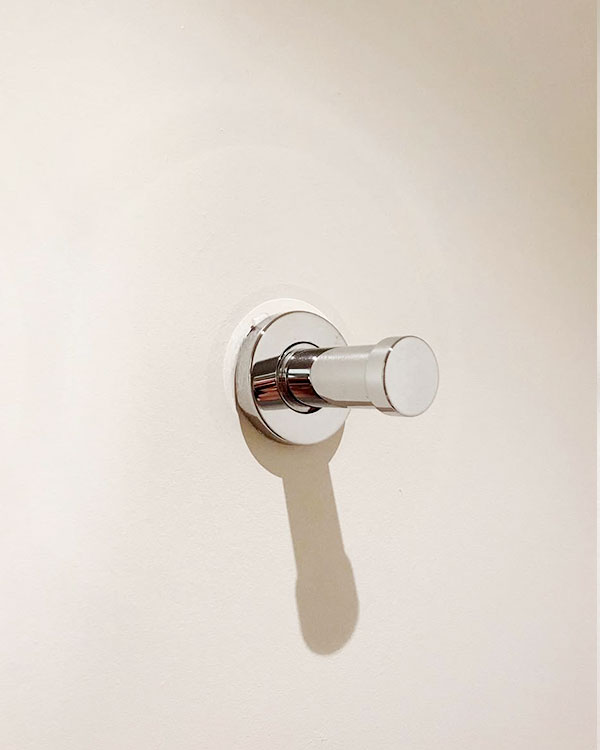 A single hook made of metal, chrome, screwed to a wall. Found on a hotel in Carcassonne, France, 2022.