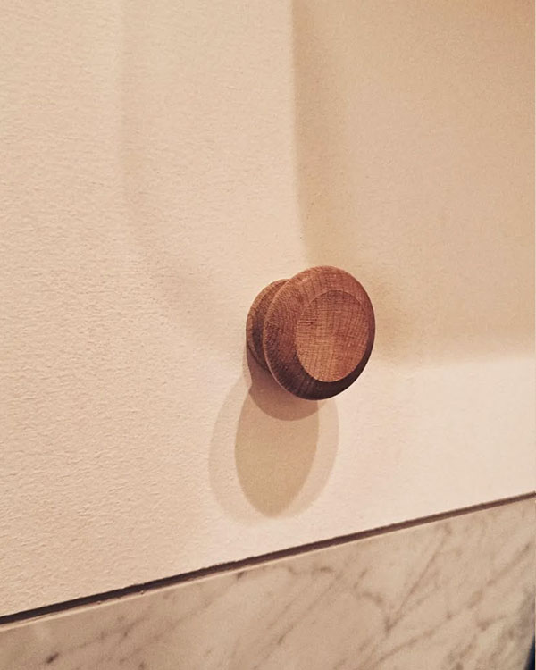 A single hook made of wood, matte varnished, fixed to a wall. Found on a private home in Montreal, Canada, 2024.
