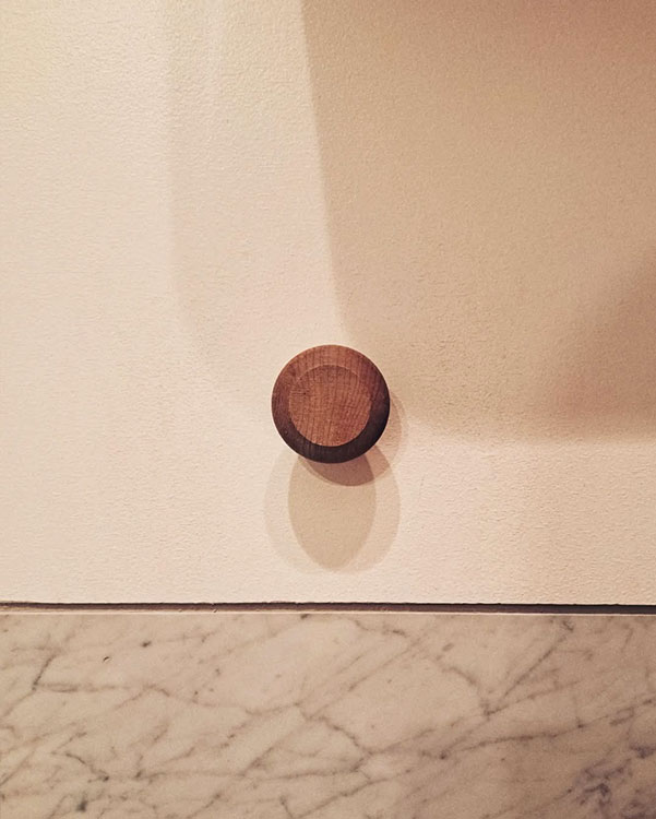A single hook made of wood, matte varnished, fixed to a wall. Found on a private home in Montreal, Canada, 2024.