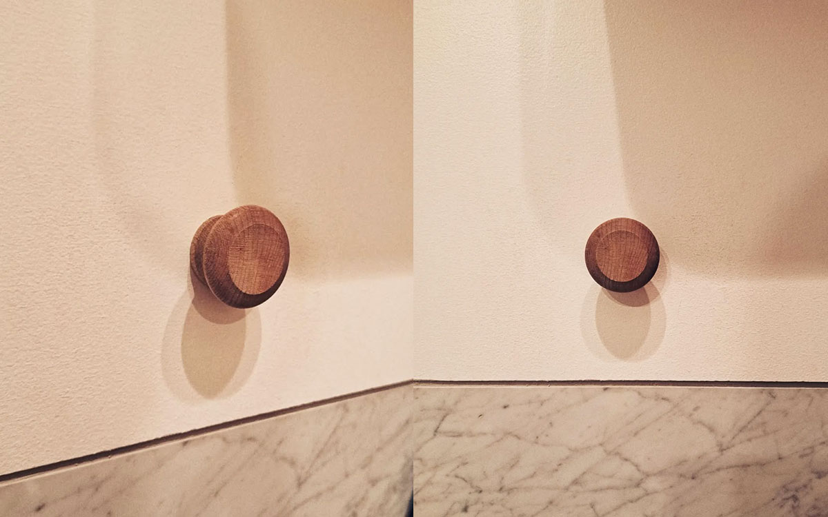 A single hook made of wood, matte varnished, screwed to a wall. Found on a private home in Montreal, Canada, 2024.