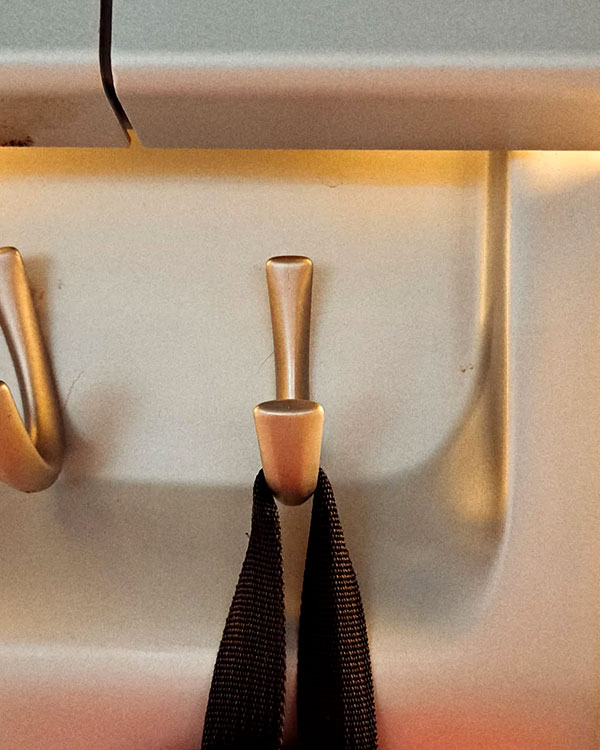 A single hook made of metal, nickel, fixed to a wall. Found on a train near Madrid, Spain, 2024.