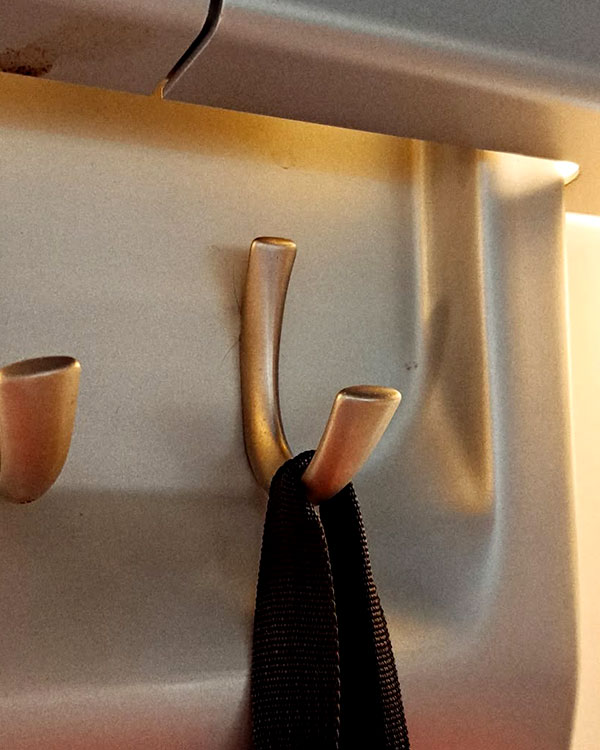 A single metal hook, nickel, screwed to a wall. Found on a train near Madrid, Spain, 2024.