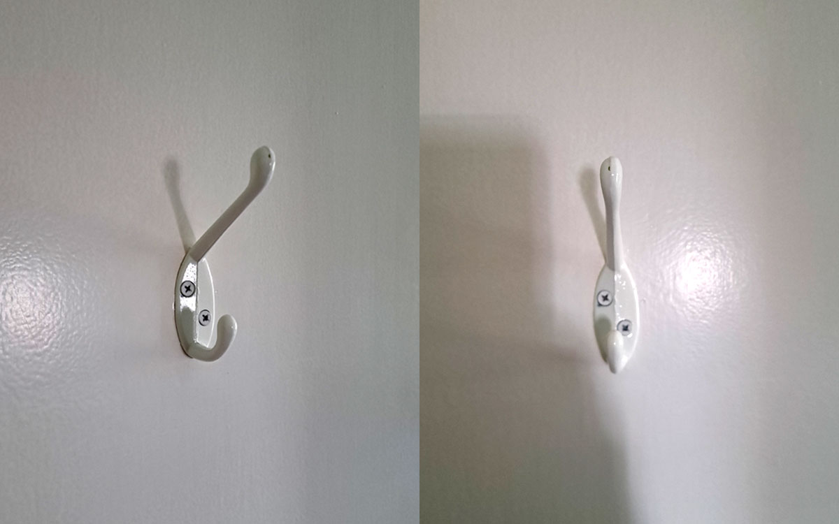 A double hook made of metal, white coating, screwed to a door. Found on a private home in New York, USA, 2025.