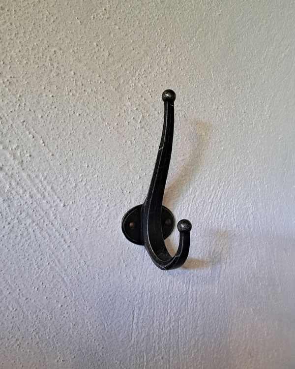A double hook made of metal, nickel, nailed to a wall. Found on a private home in Tepoztlan, Mexico, 2025.