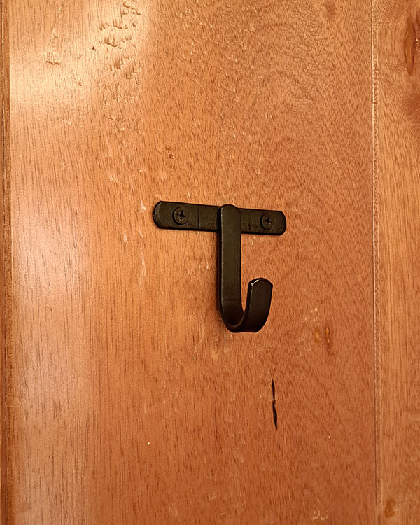 A single hook made of metal, nickel, screwed to a door. Found on a restaurant in Mexico City, Mexico, 2025.