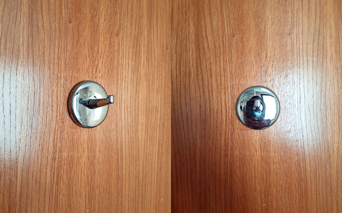 A single hook made of metal, chrome, screwed to a door. Found on a hotel in Porto, Portugal, 2025.