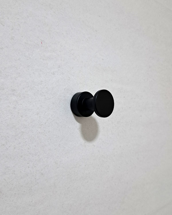 A single hook made of metal, nickel, screwed to a wall. Found on a museum in Porto, Portugal, 2025.
