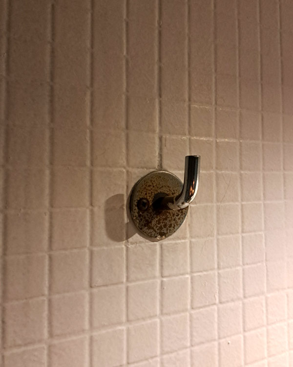 A single hook made of metal, chrome, screwed to a wall. Found on a bar in Barcelona, Spain, 2025.