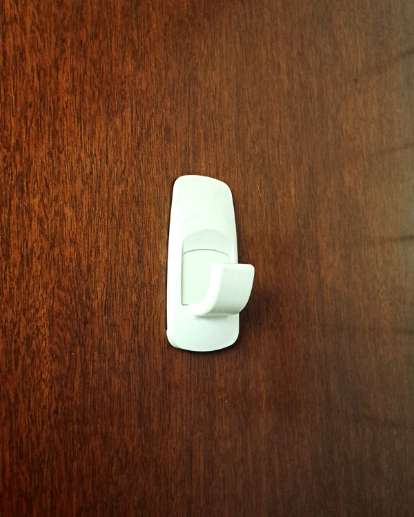 A single hook made of white plastic, screwed to a door. Found on a home in Mexico City, Mexico, 2025.
