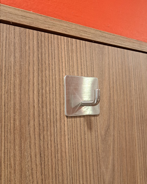A single hook made of metal, nickel, glued to a door. Found on a restaurant in Mexico City, Mexico, 2026.