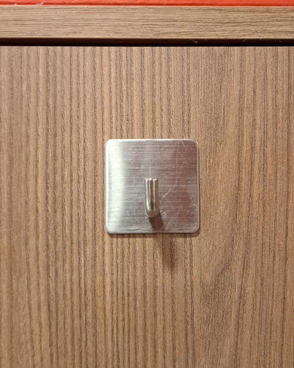 A single hook made of metal, nickel, glued to a door. Found on a restaurant in Mexico City, Mexico, 2026.