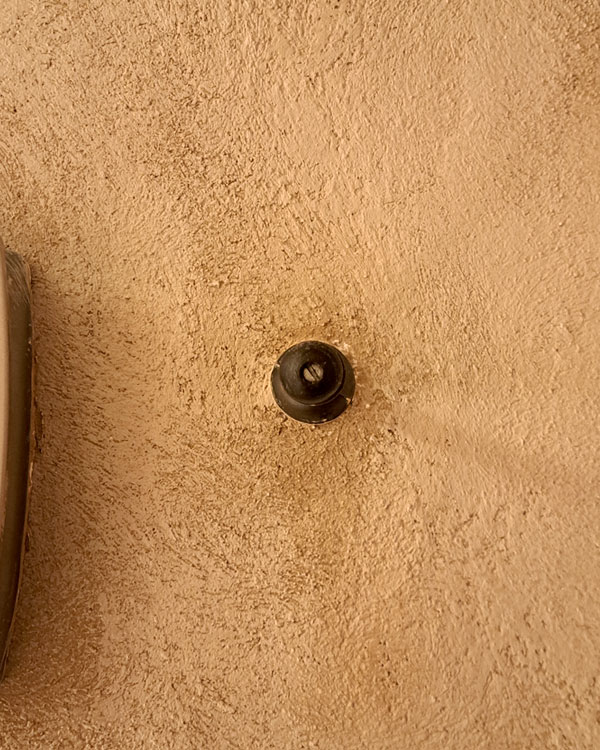 A single hook made of metal and plastic, nickel, screwed to a wall. Found on a restaurant in Mexico City, Mexico, 2026.