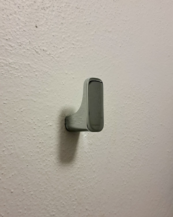 A single hook made of metal, chrome, fixed to a wall. Found on a home in Mexico City, Mexico, 2026.