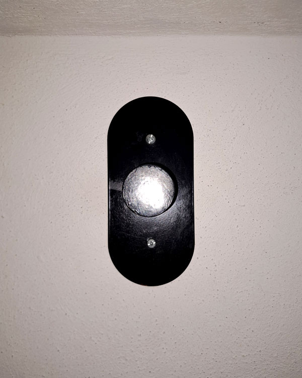 A single hook made of metal, black powder, screwed to a wall. Found on a restaurant in Mexico City, Mexico, 2026.