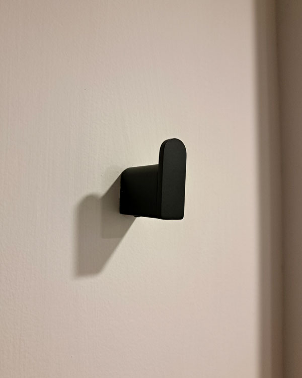 A single hook made of metal, black powder, fixed to a wall. Found on a private home in Mexico City, Mexico, 2026.