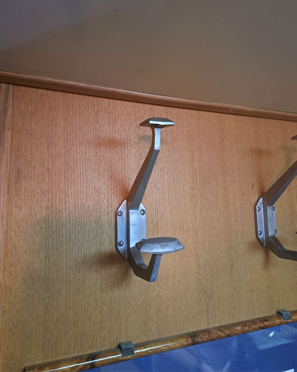 A double hook made of metal, nickel, screwed to a wall on a museum in Paris, France, 2026.