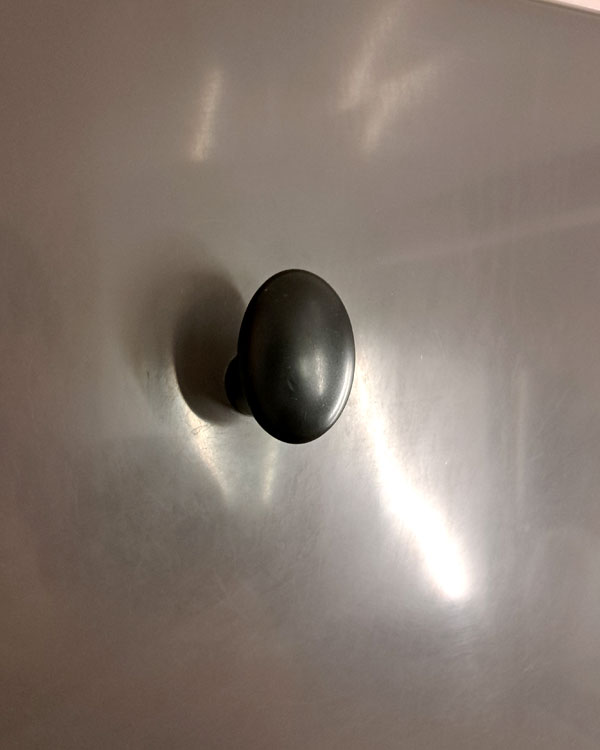 A single hook made of black plastic, fixed to a wall on a train near Paris, France, 2026.