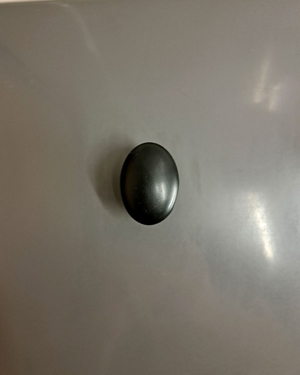 A single hook made of black plastic, fixed to a wall on a train near Paris, France, 2026.