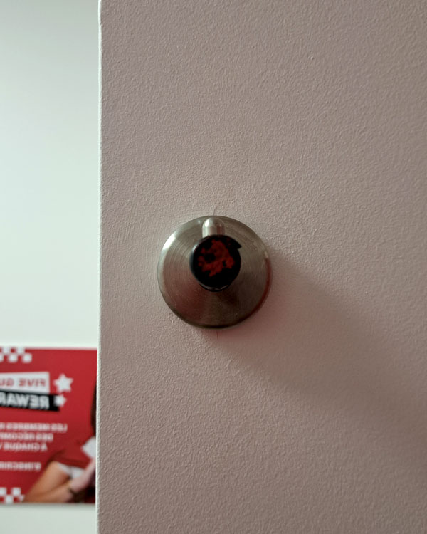 A single hook made of metal, nickel, fixed to a wall on a restaurant in Lyon, France, 2026.