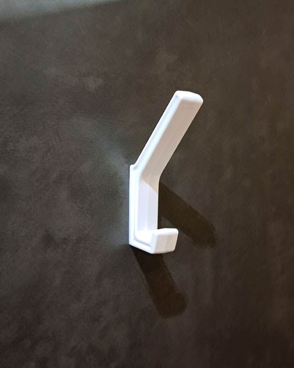 A double hook made of white plastic, fixed to a door on a public pool in Lyon, France, 2026.