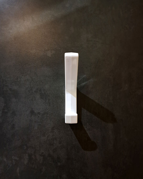 A double hook made of white plastic, fixed to a door on a public pool in Lyon, France, 2026.