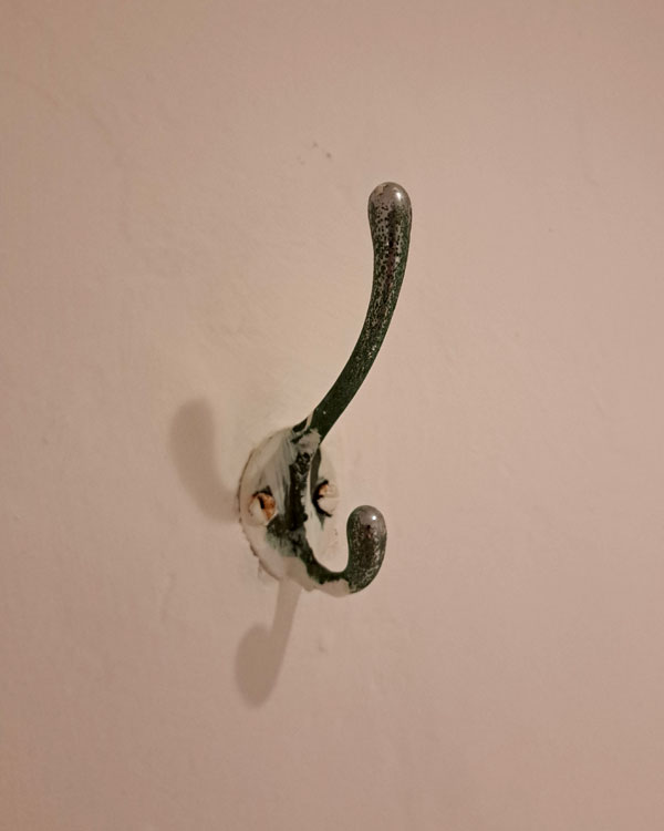 A double hook made of metal, chrome, screwed to a wall on a restaurant in Mexico City, Mexico, 2026.